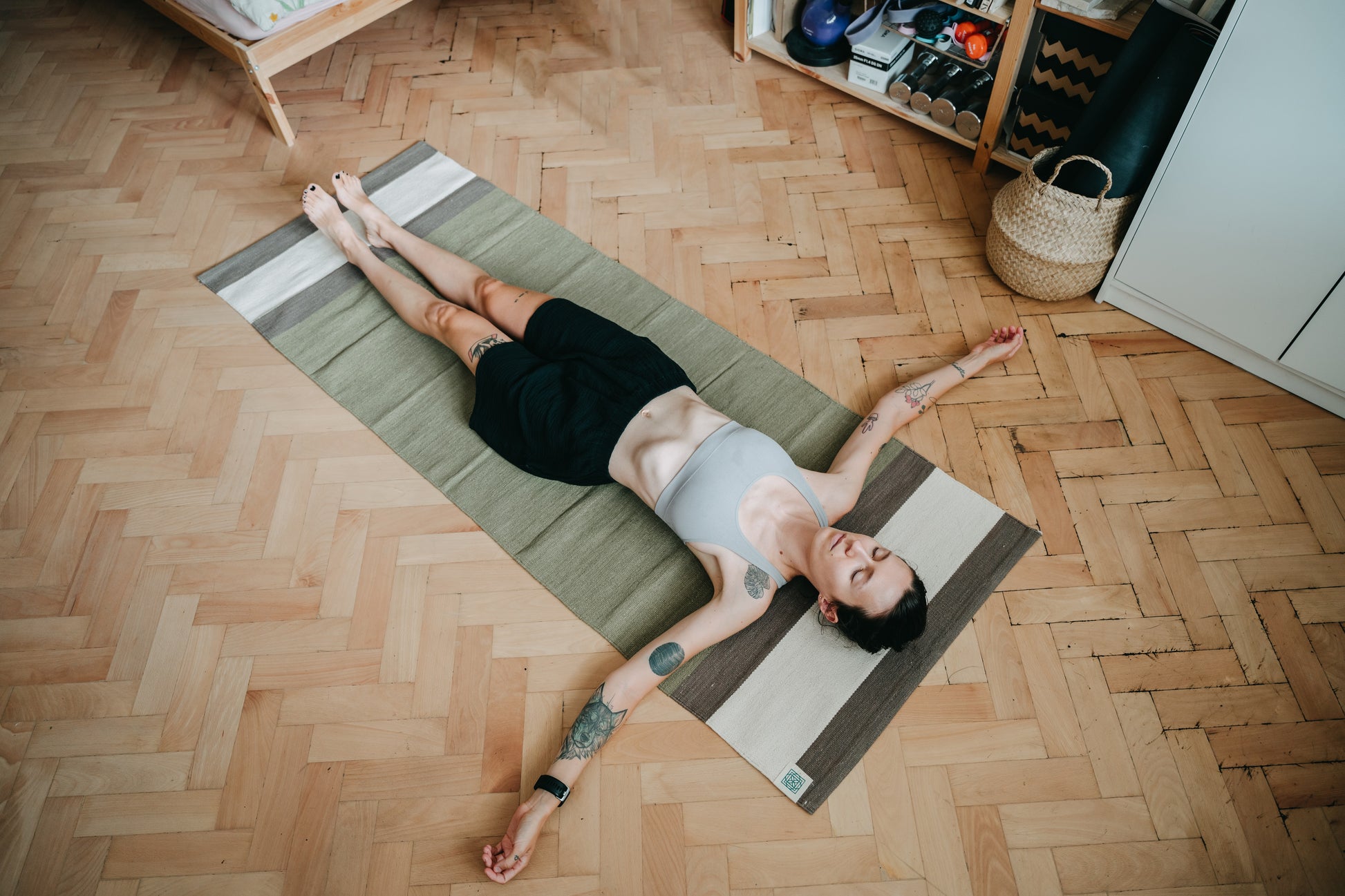 Young women resting on green cotton yoga rug on wooden floor in her room